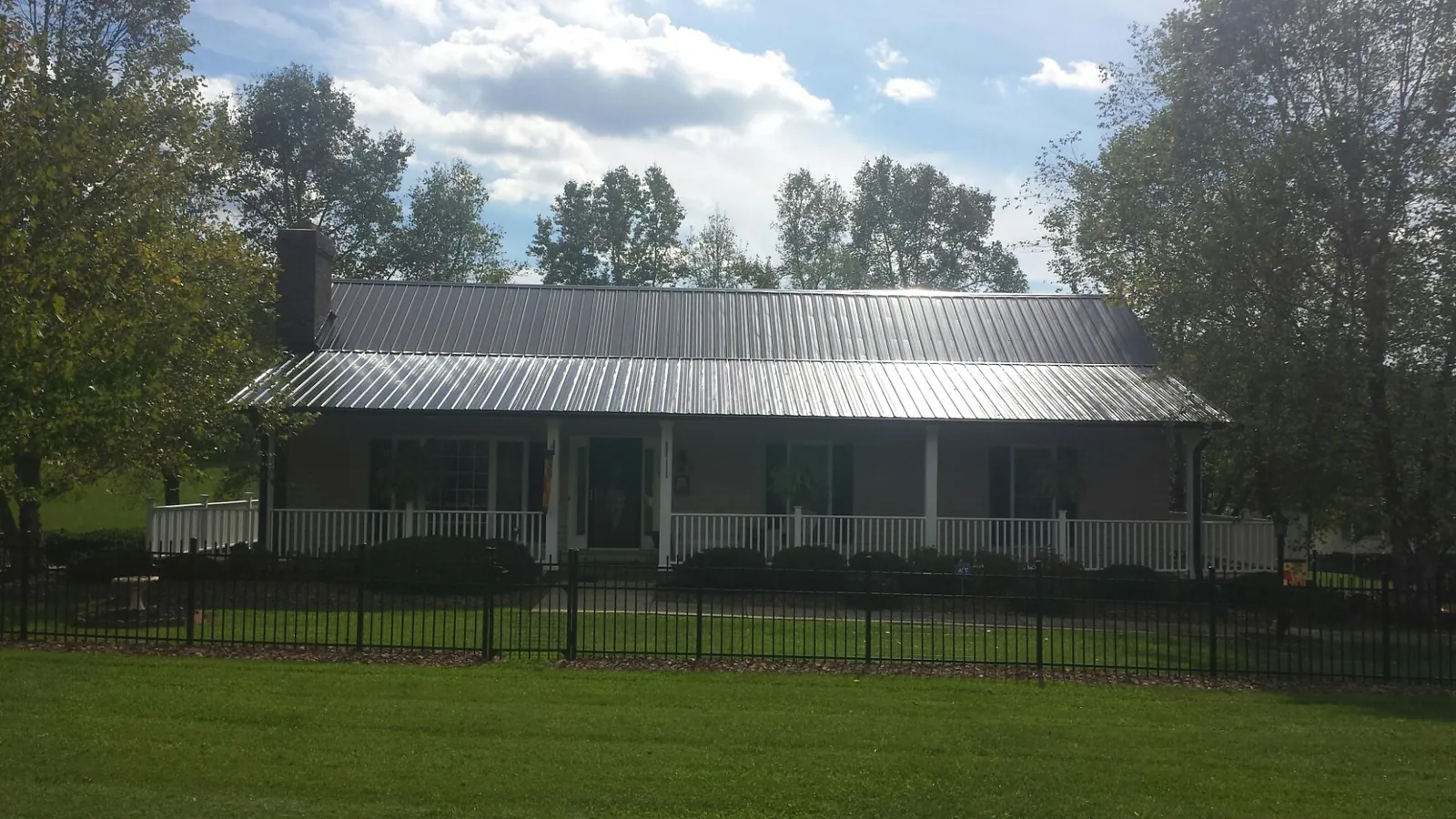 Gray metal roof on a brick ranch with a full width front porch — Gutter Guard Installation work by our crew in Cypress