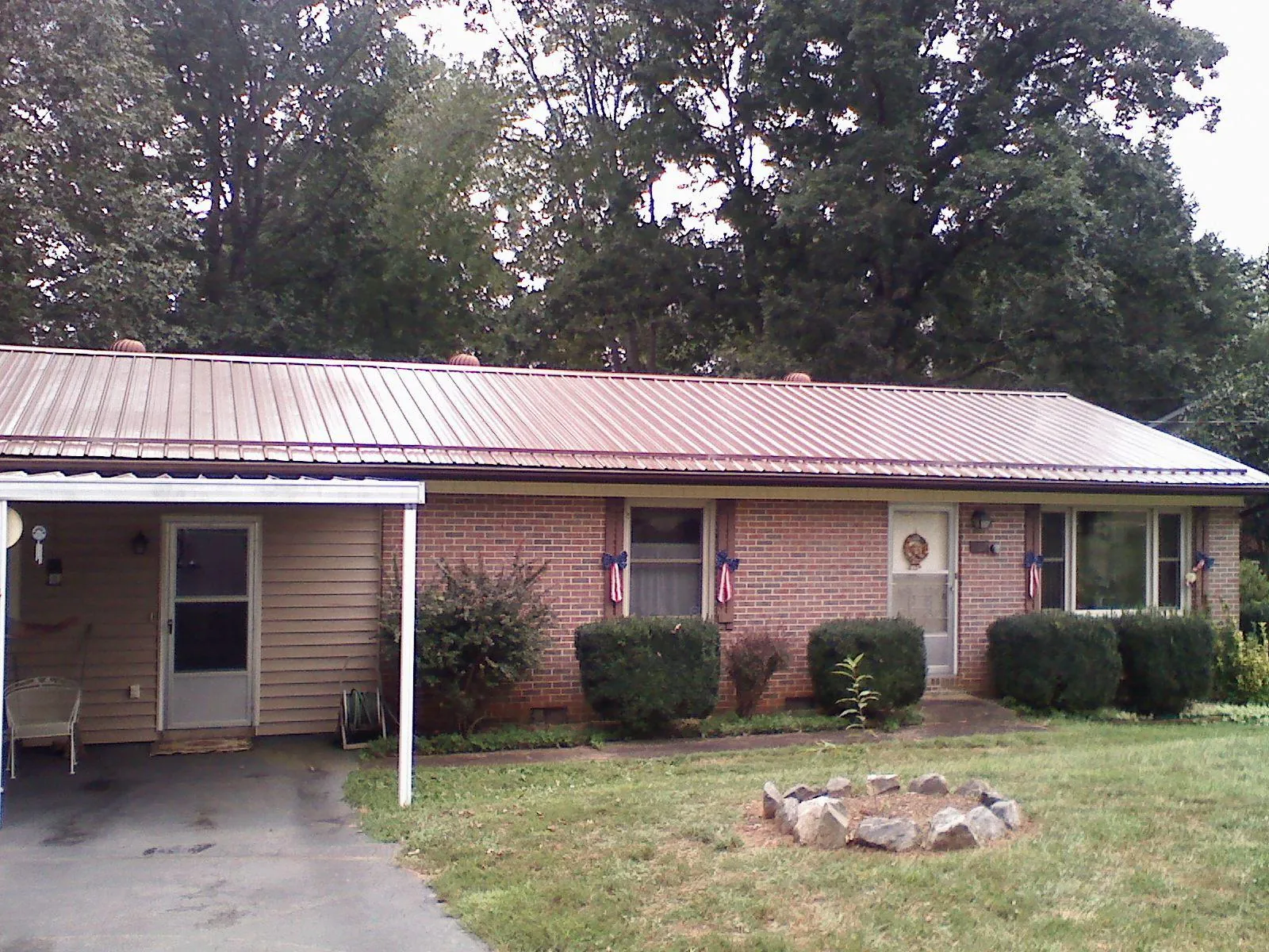 Bronze metal roof and carport on a brick ranch home — Roof Repair work by our crew in Cypress